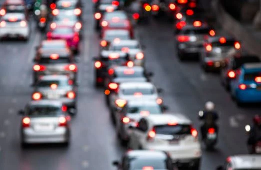 Trânsito intenso com muitos carros na rua durante o pôr do sol, criando um cenário de congestionamento na cidade.